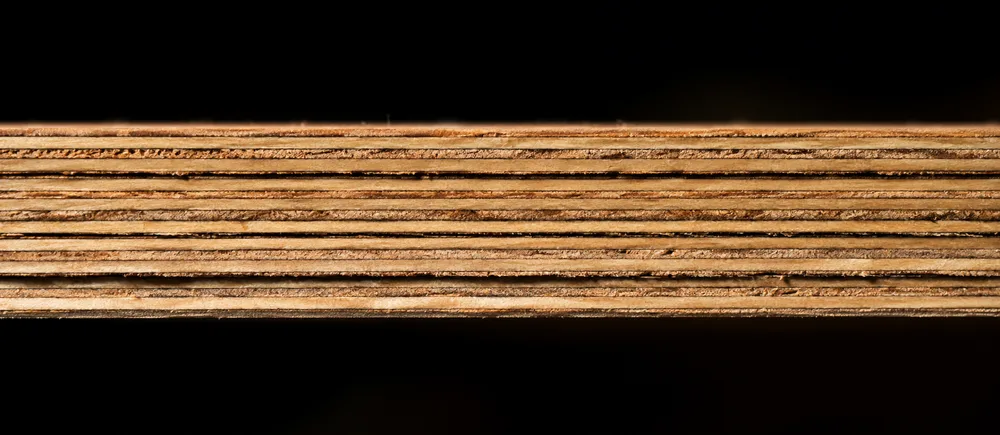 The cut edge of a stack of plywood sheets, showing the layered plies inside each one